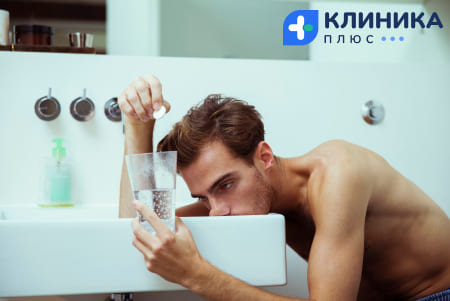 Человек держит стакан и таблетку