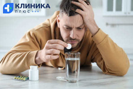Человек держит таблетку над стаканом