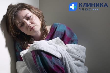Женщина сидит облокотившись на стену
