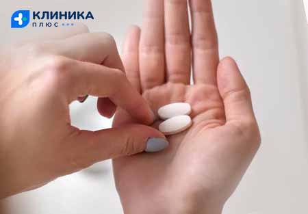 Две таблетки анальгетиков в ладони